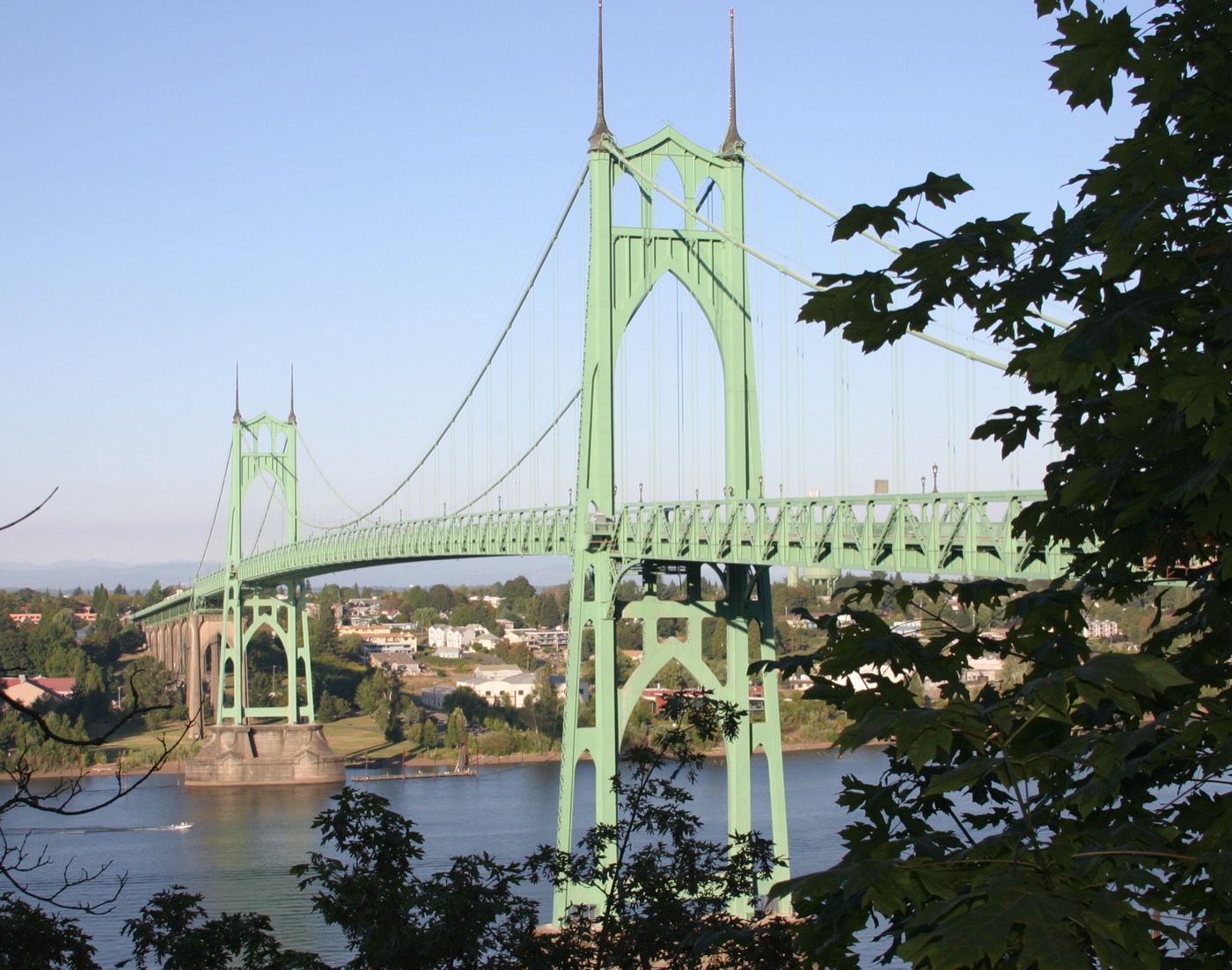 St. Johns Bridge over the Willamette River in Portland, framed by green leaves.